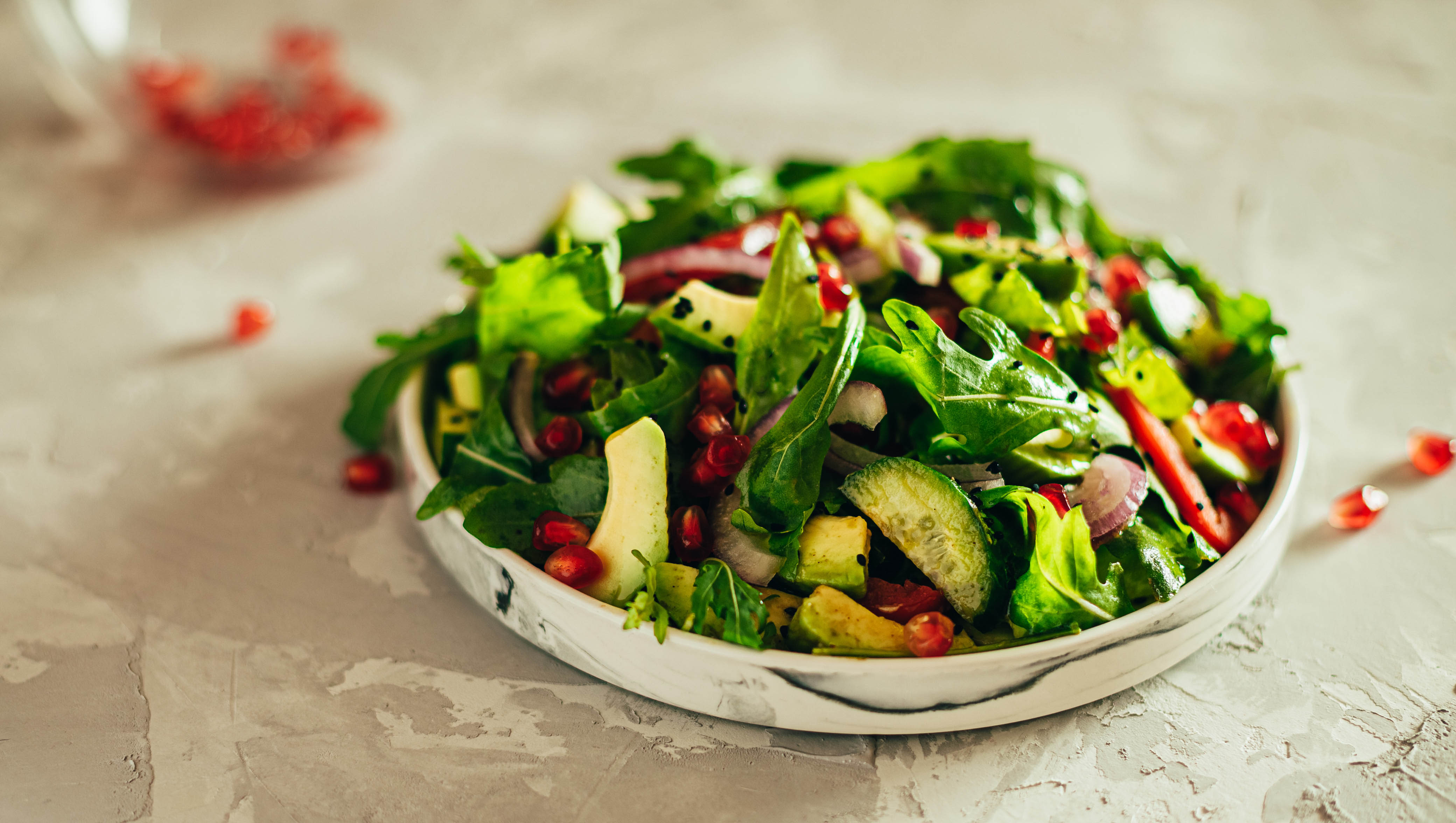 Close-up of greens and pomegranate salad with cucumbers and sesame seeds